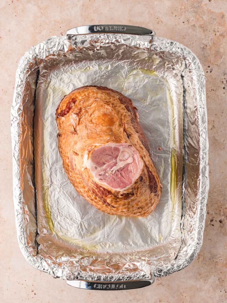 A ham in a roasting tray flat side down.