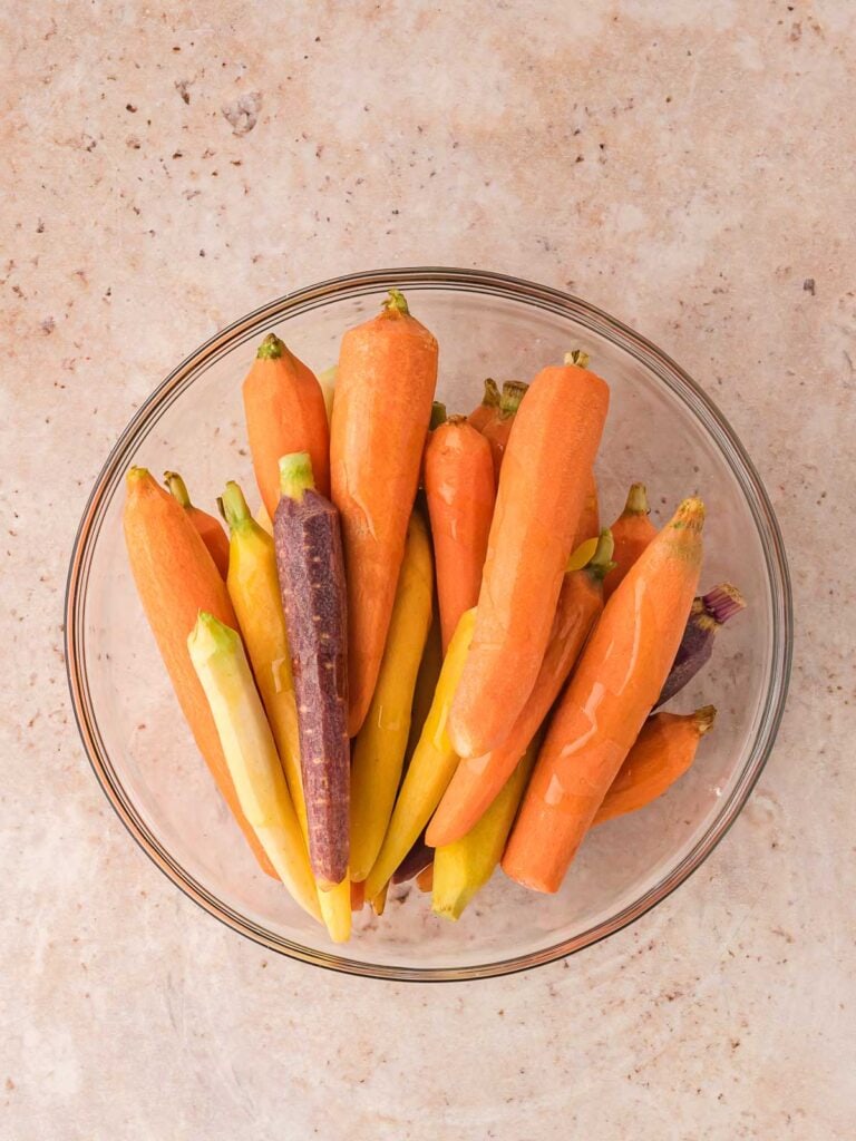 Carrots in a bowl with oil over them.