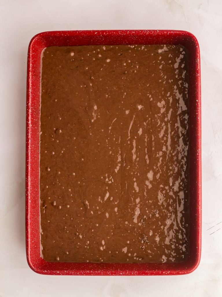 Chocolate cake mix in a red 9x13 dish.