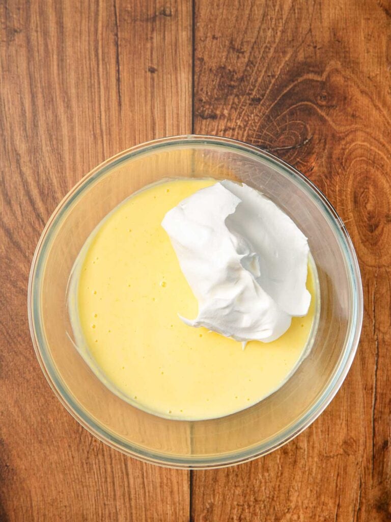 Mixed pudding with cool whip on top in a bowl.