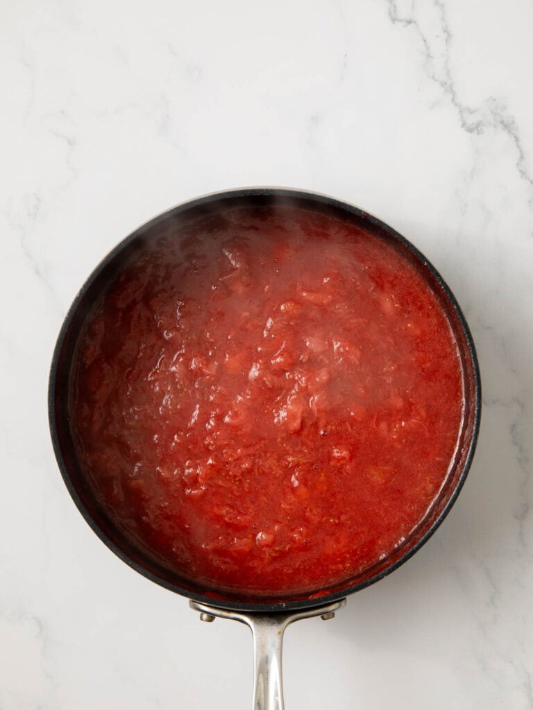 Strawberries cooked down in a pot to make strawberry sauce.