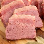 Up close of a slice of corned beef on a wooden board.