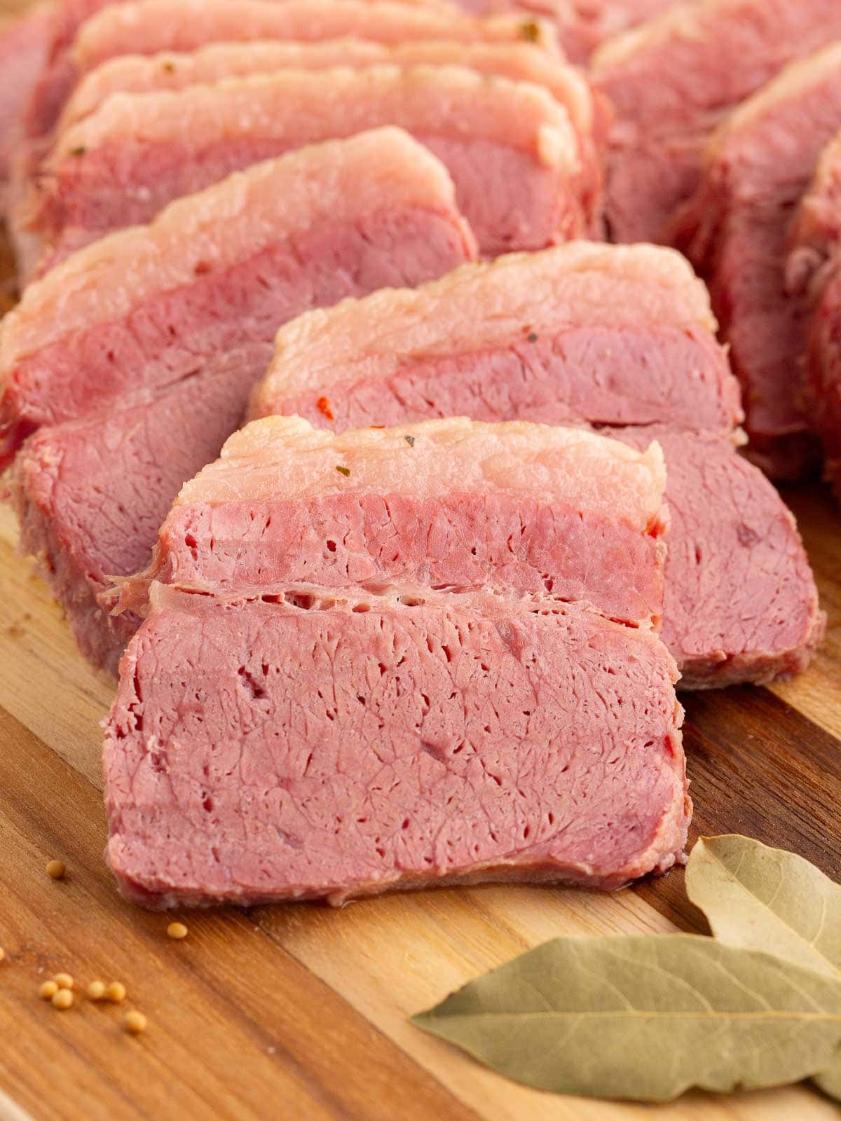 Up close of a slice of corned beef on a wooden board.