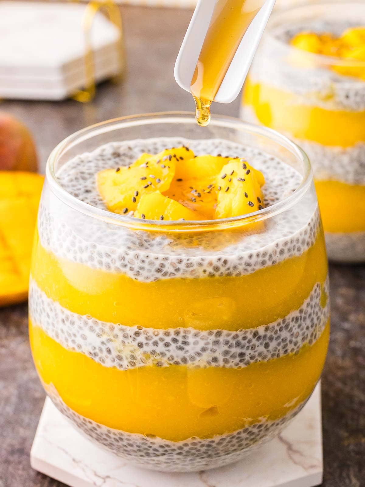 Honey being poured onto a layers of Mango Chia Pudding.