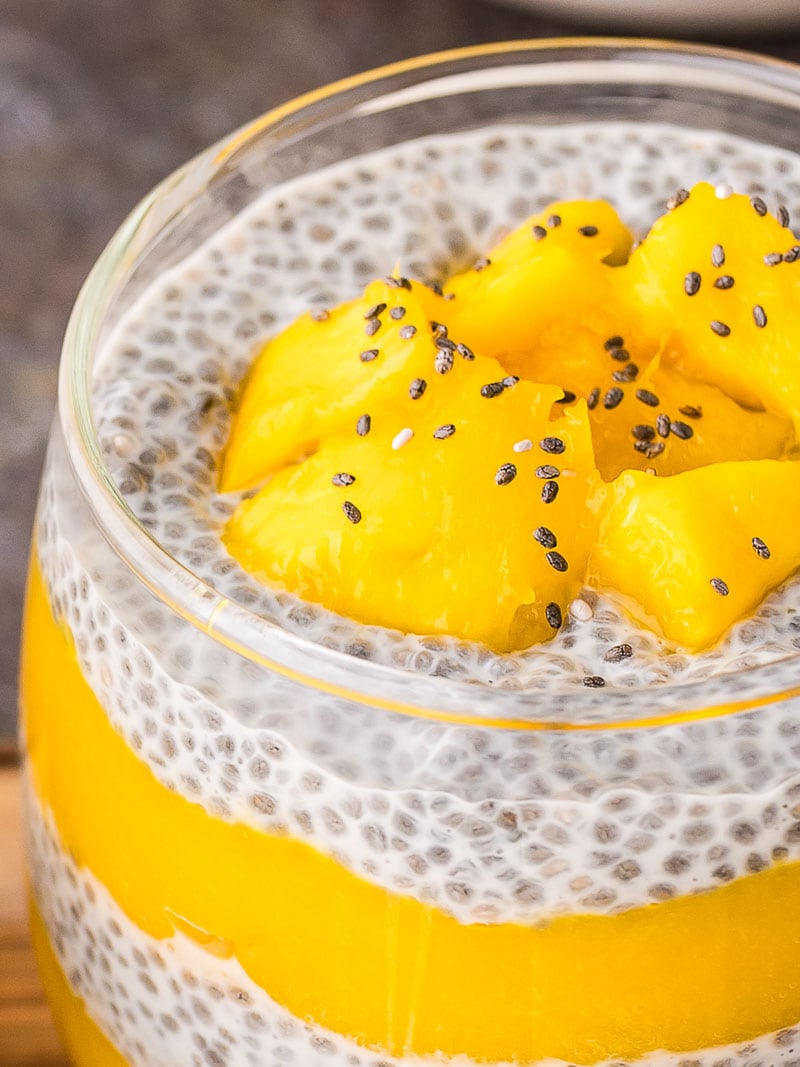 Up close of the inside of a glass with Mango Chia Pudding in it with chia seeds sprinkled on top.