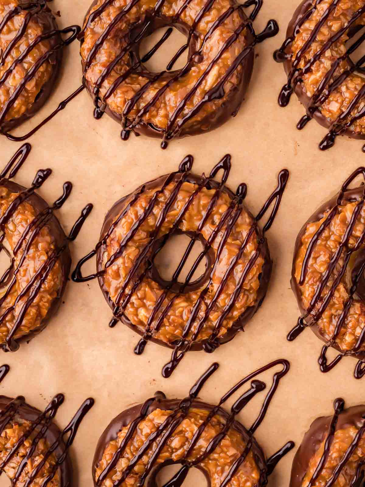 An over head photo of Samoas Cookies on brown parchment paper with chocolate drizzle.