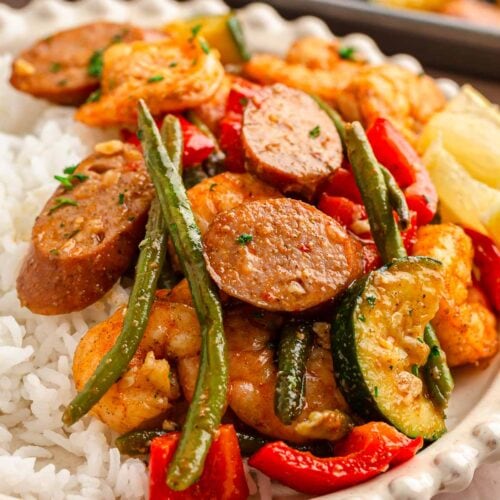 Up close 45 degree angle of shrimp and veggies served with rice on a white plate.