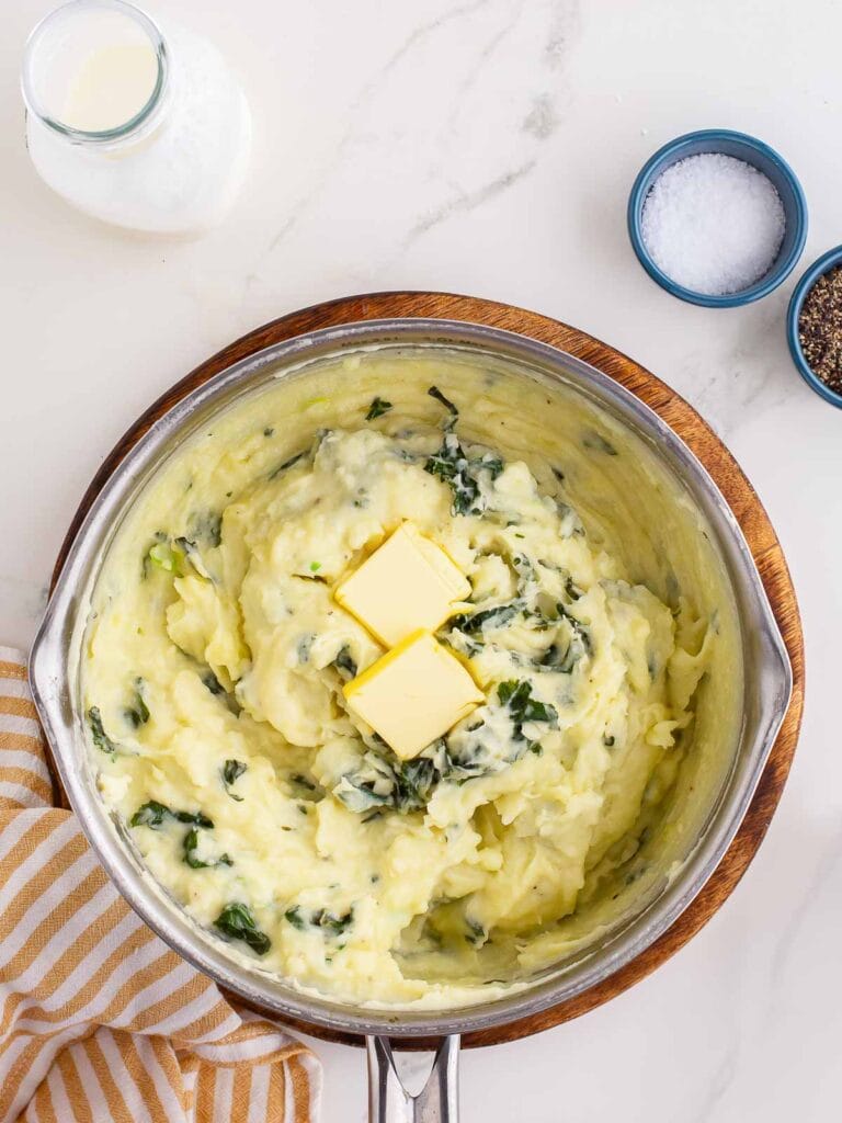 Mashed Colcannon in a pot with two butter pats.