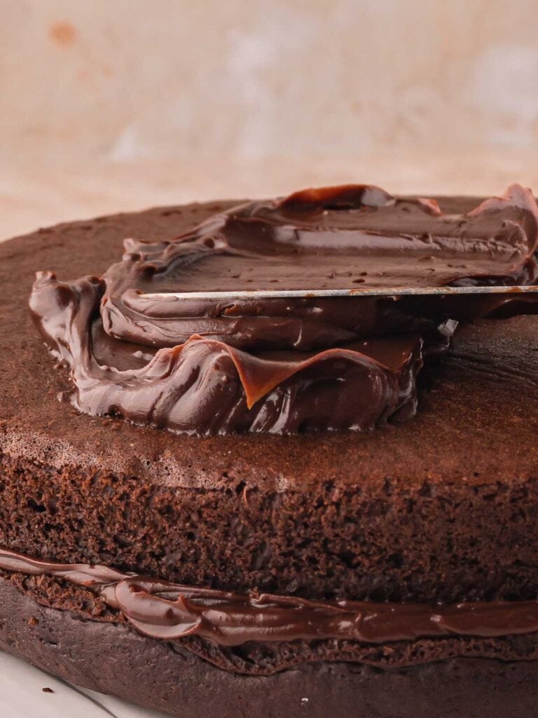 Chocolate ganache being spread onto double chocolate cake.