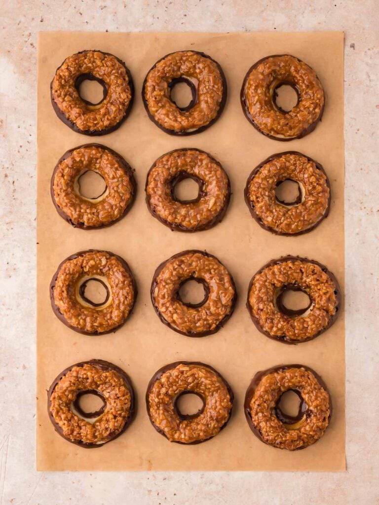 Chocolate dipped samoas cookies resting on parchment paper.