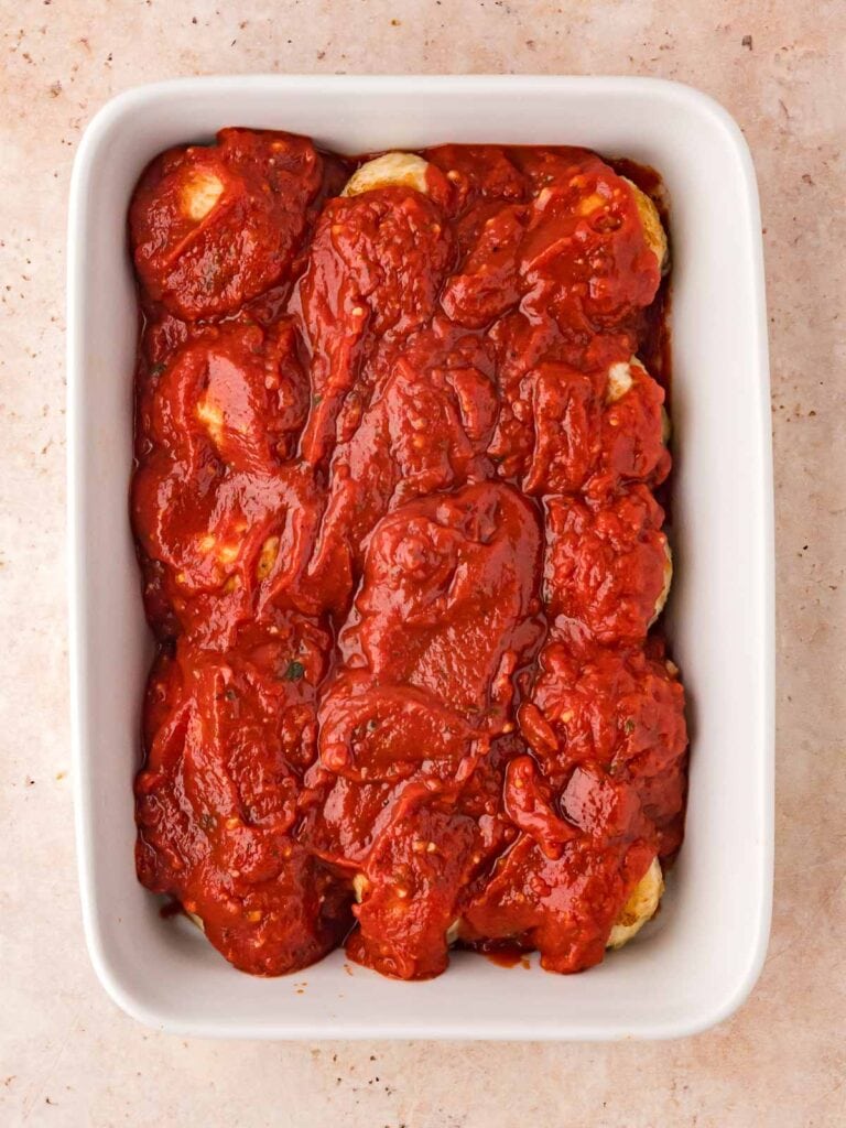 Marinara sauce poured on top of the turkey meatballs in a casserole dish.