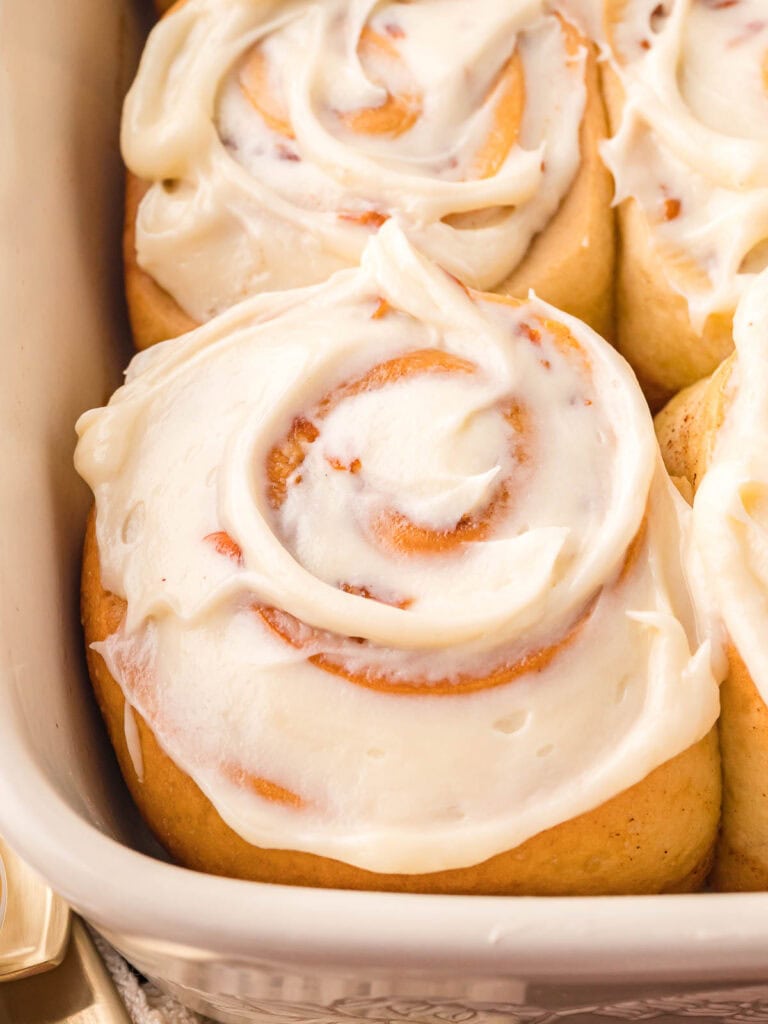 Up close of a carrot cake cinnamon roll with cream cheese frosting.