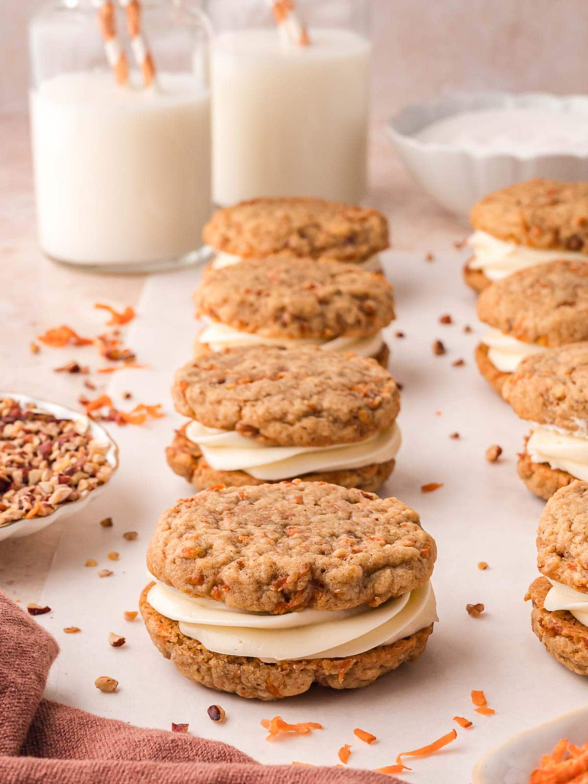 Carrot Cake Cookie Sandwiches in rows on a table with scattered ingredients.