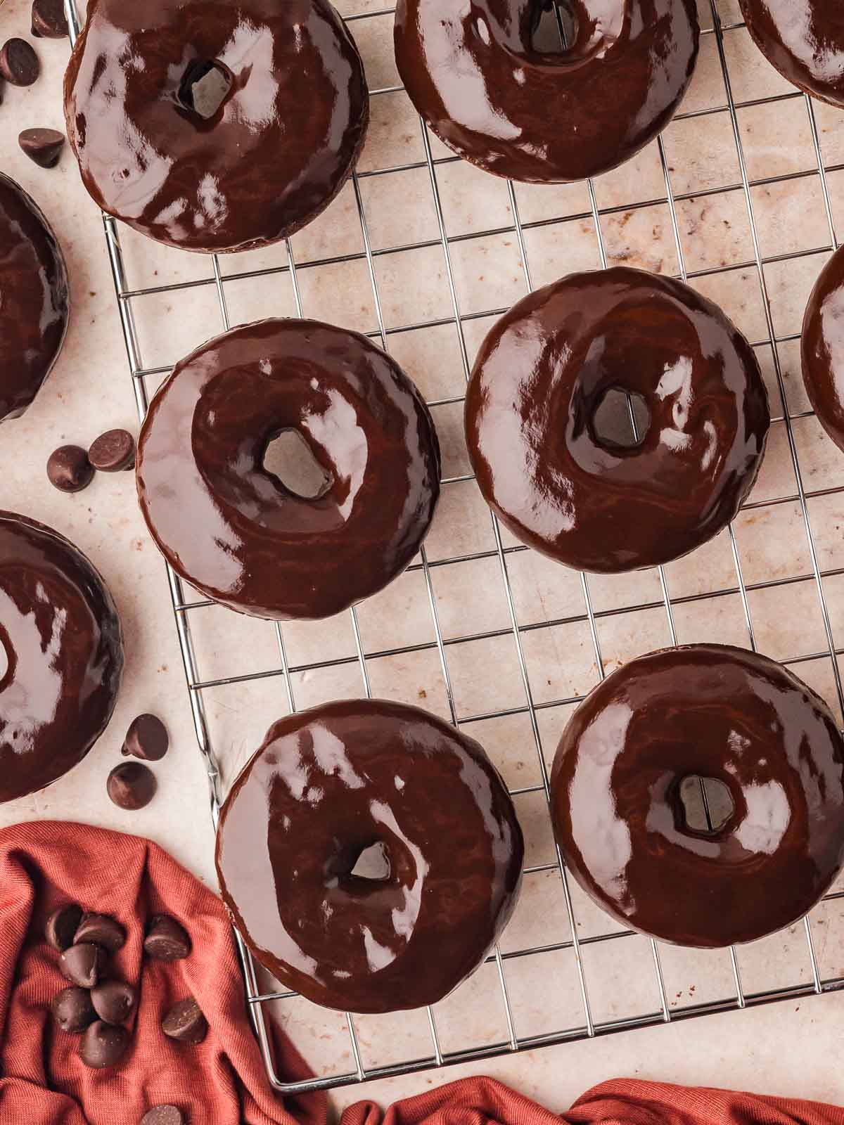 Chocolate glazed donuts on a wire rack.