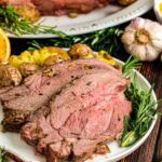 Plated up slices of roast leg of lamb on a [late with fresh herbs.