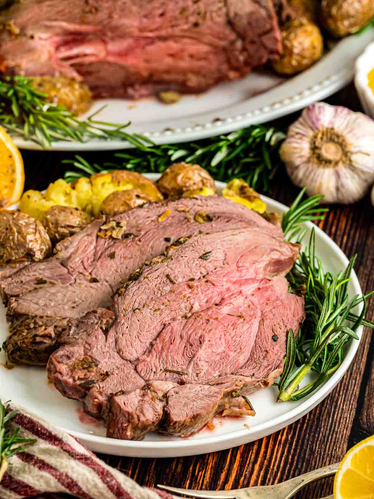 Plated up slices of roast leg of lamb on a [late with fresh herbs.