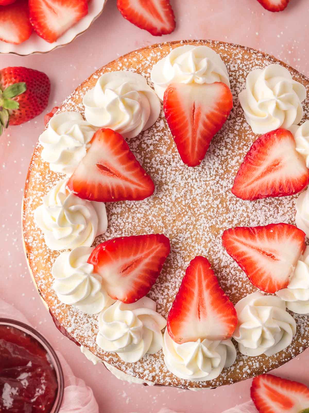 Overhead shot of Victoria Sponge with fresh whipped cream and fresh sliced strawberries.