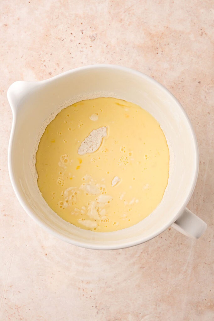 Milk and eggs mixture poured ontop of dry ingredients in a mixing bowl.