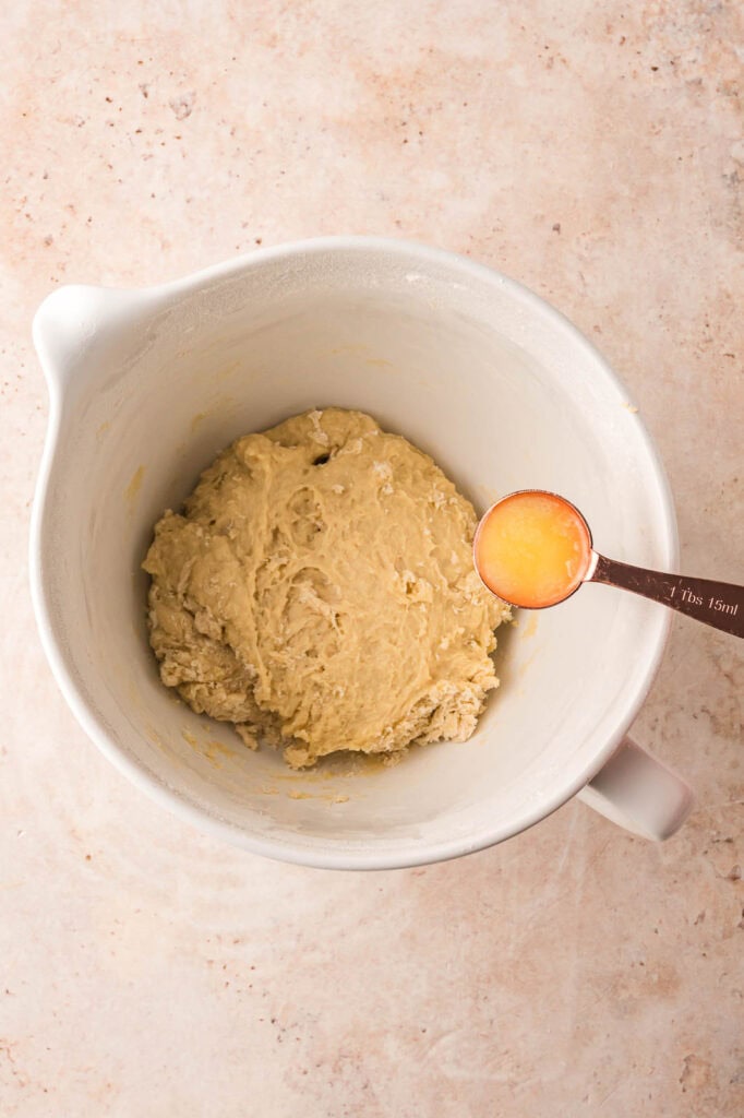 Adding butter to the dough in the mixing bowl.