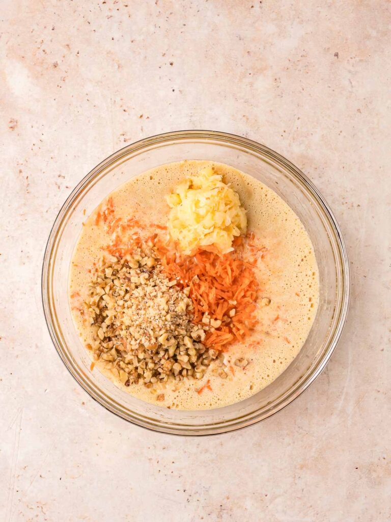 Carrots, pineapple and nuts in a bowl with the cake mixture.