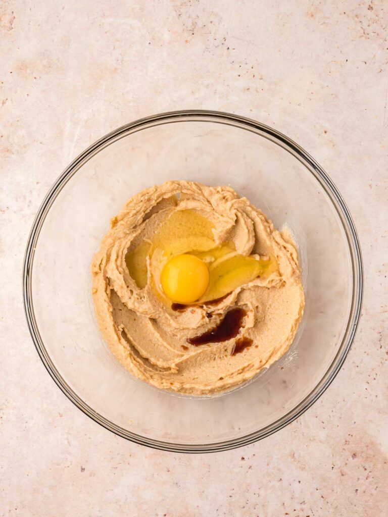 Egg and vanilla in a bowl with the creamed butter and sugar.