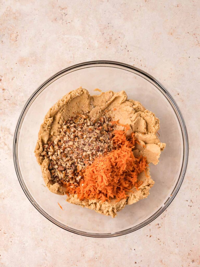 Carrots and nuts in a bowl with the cookie batter.