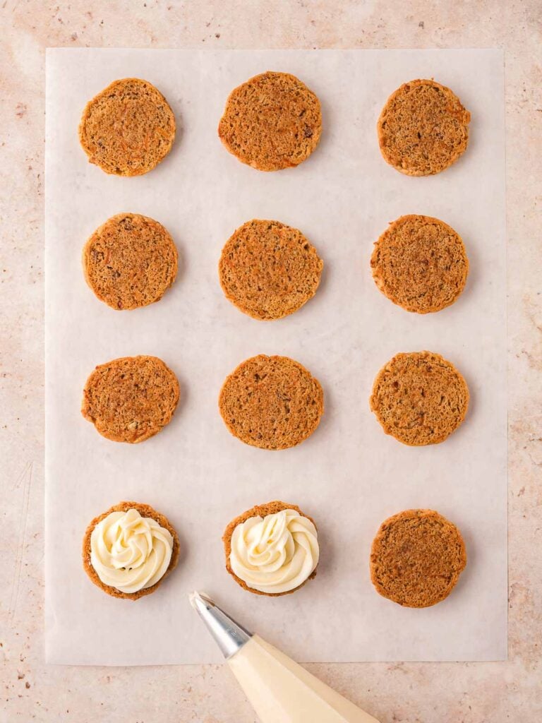 Cookies with cream cheese frosting being pipped on.