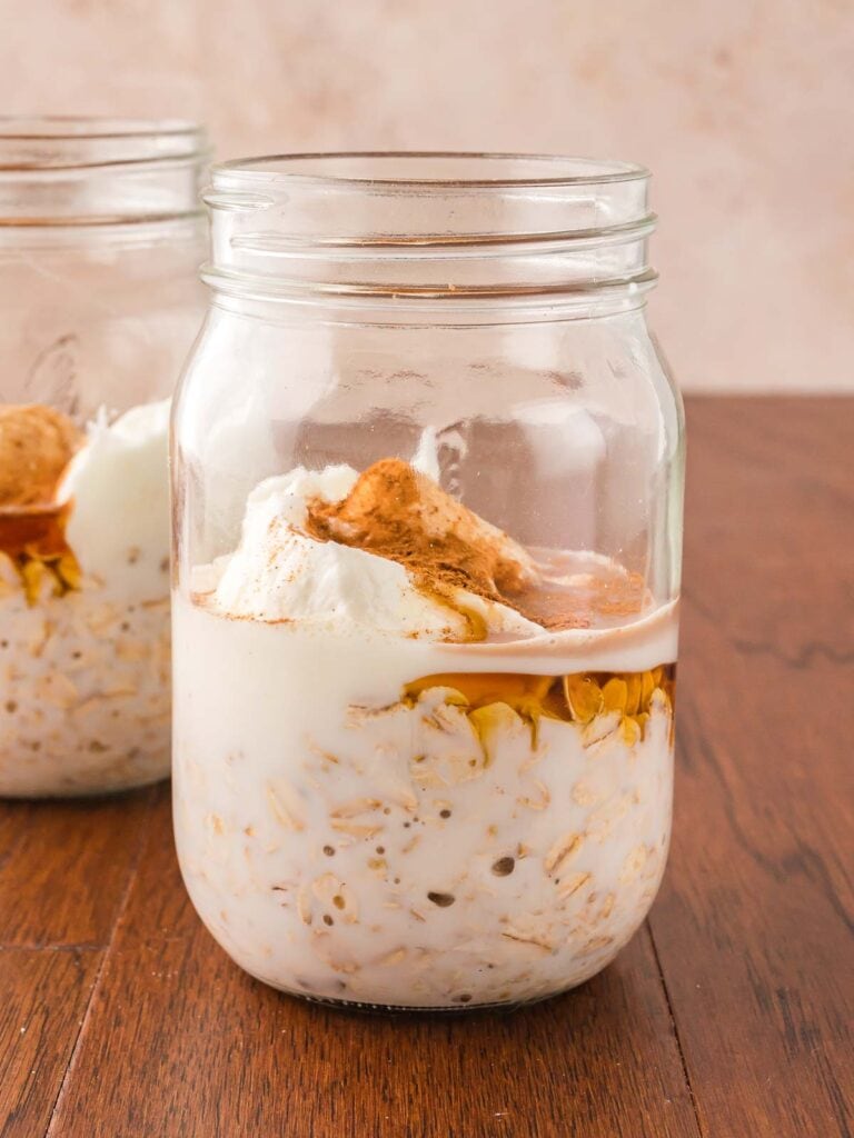 Oats, milk, Greek yogurt, maple syrup, vanilla, cinnamon, and nutmeg in a jar.