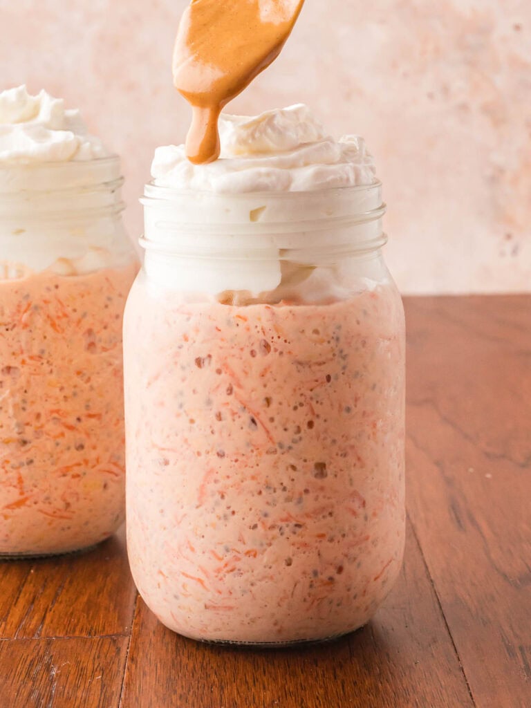 Greek yogurt and peanut butter being added to the jar with the overnight carrot cake oats.