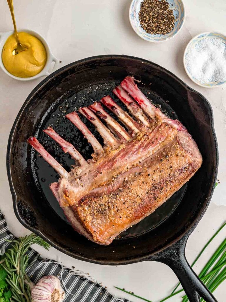 Rack of lamb seared in a cast iron pan.