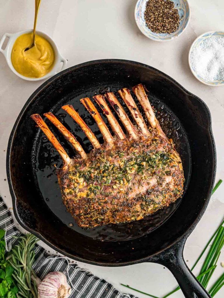 Cooked rack of lamb in a cast iron pan.