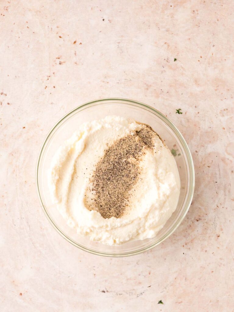 Ricotta with salt and pepper in a bowl.