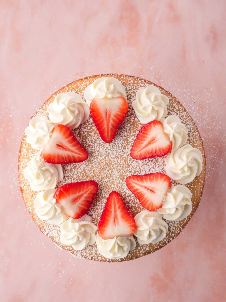 Fresh whipped cream and strawberries on the top layer of a Victoria Sponge.