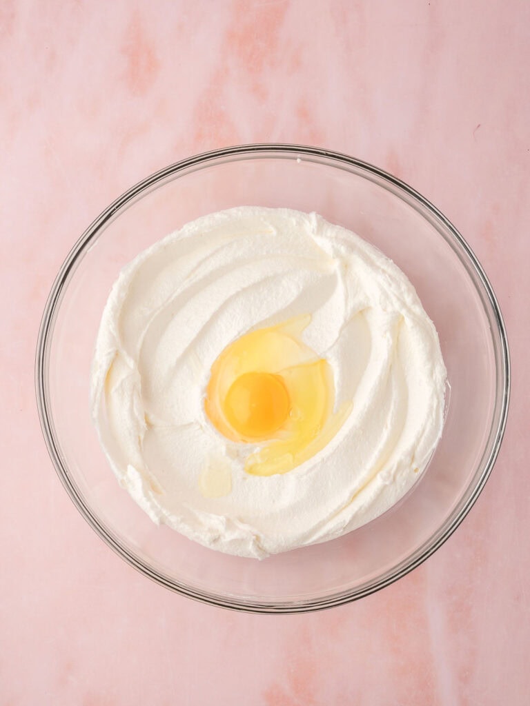 An egg being added to the butter and sugar.