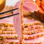 A slice of herb crusted baked ham on a fork.