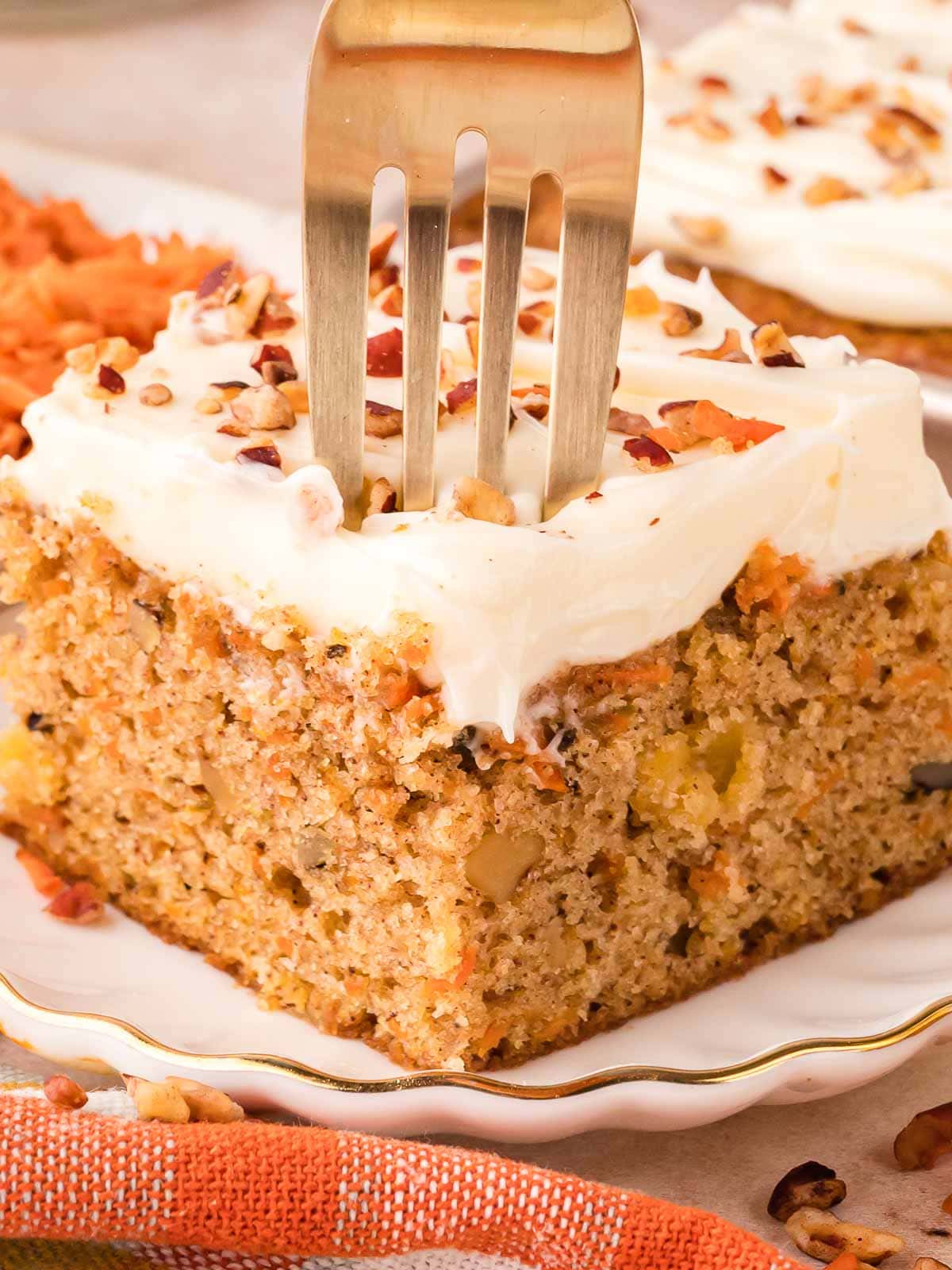 A fork slicing into the carrot cake sheet cake.