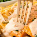 Up close of Tuscan Salmon in a pan with creamy sauce poured on top and a gold fork ready to dig in.