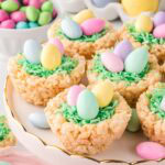 Cute Rice Krispie Easter Nests on a white serving plate with chocolate eggs in the background.