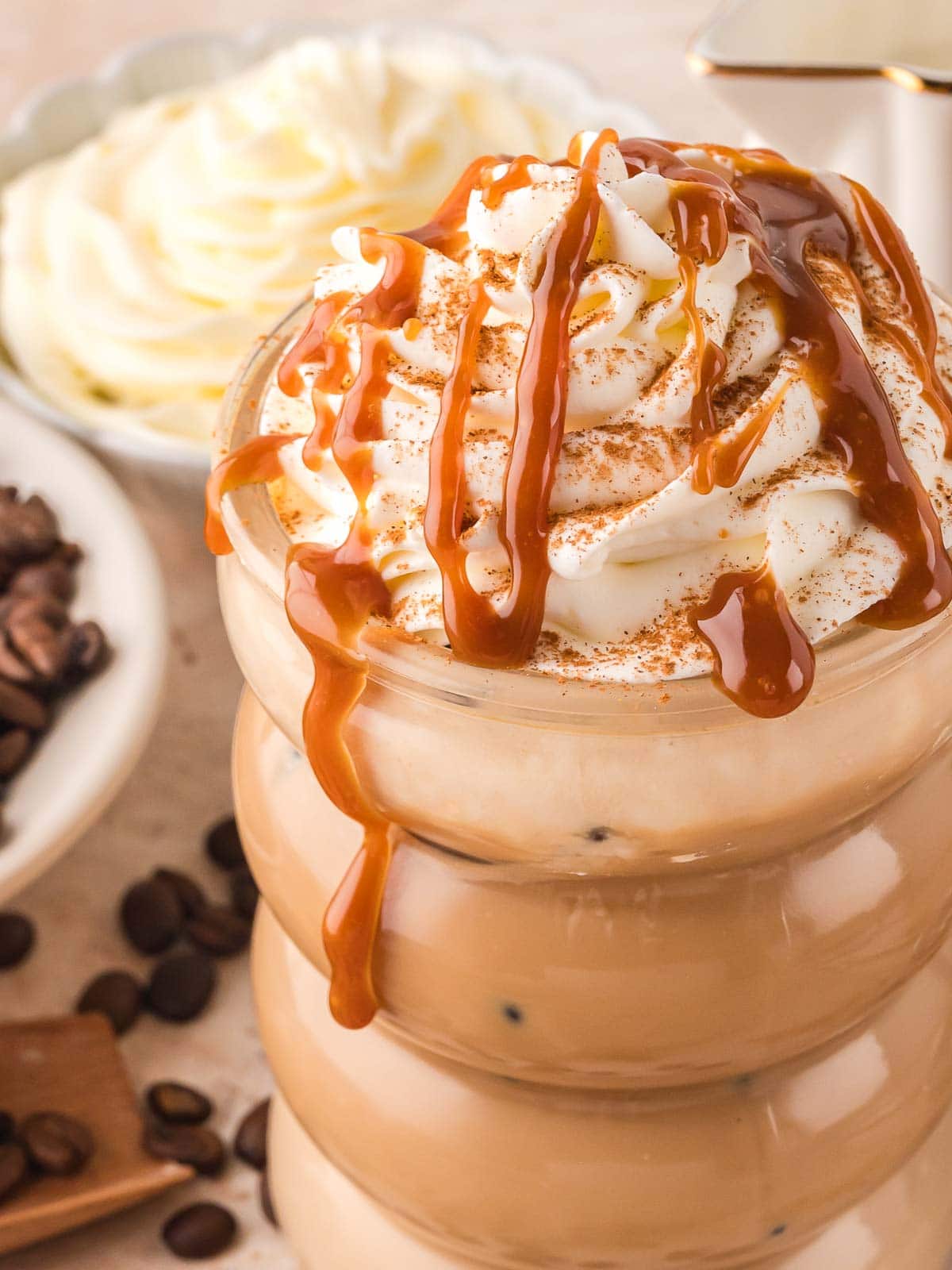 Up close of a Tres Leches Iced Coffee with whipped cream, cinnamon and caramel drizzled on top.