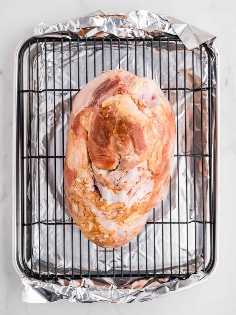 A Cooked ham on a roasting tray ready to be baked.