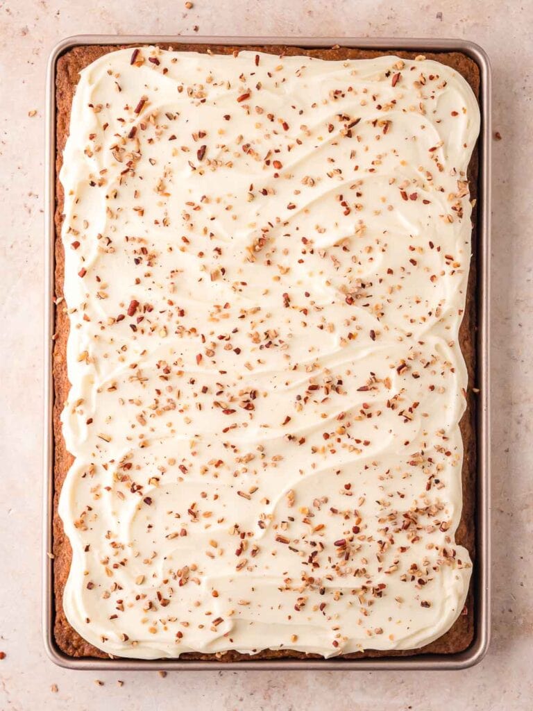 The frosting and walnuts spread on top of the carrot cake sheet cake.