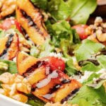 Up close of Grilled Peach Salad on a plate with honey on the peaches.
