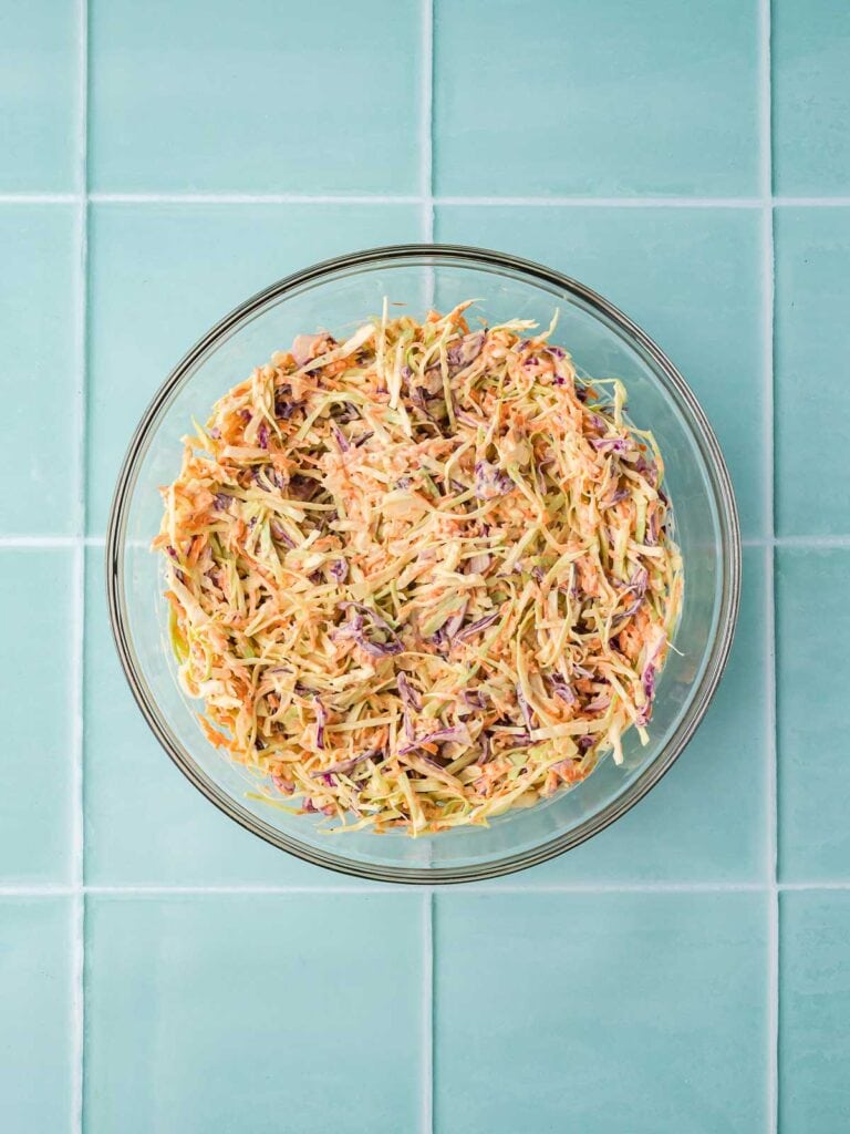 Fully mixed creamy coleslaw in a glass bowl, ready to chill and serve.