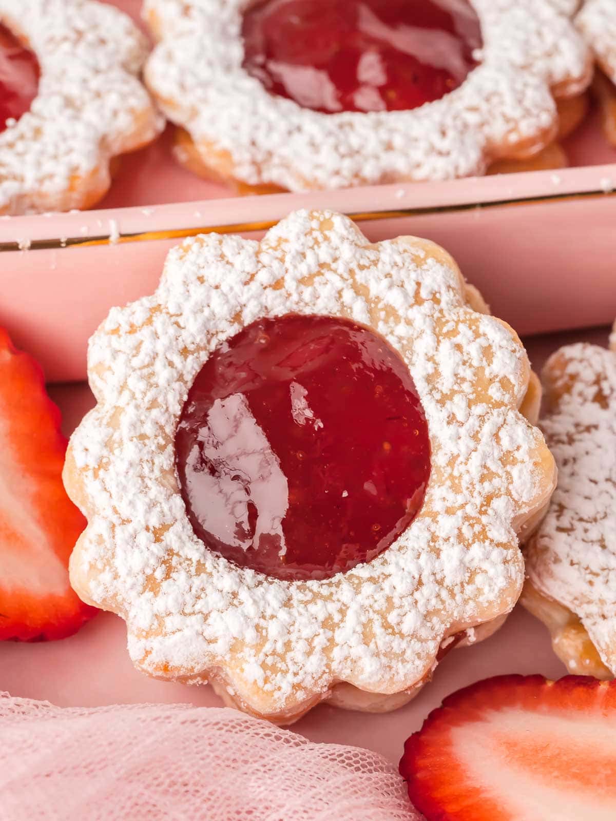 Zoomed-in view of one strawberry pie cookie showing glossy strawberry jam and powdered edges.