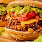 Close-up of the taco meat filling loaded with corn and beans under layers of guacamole and fresh tomatoes.