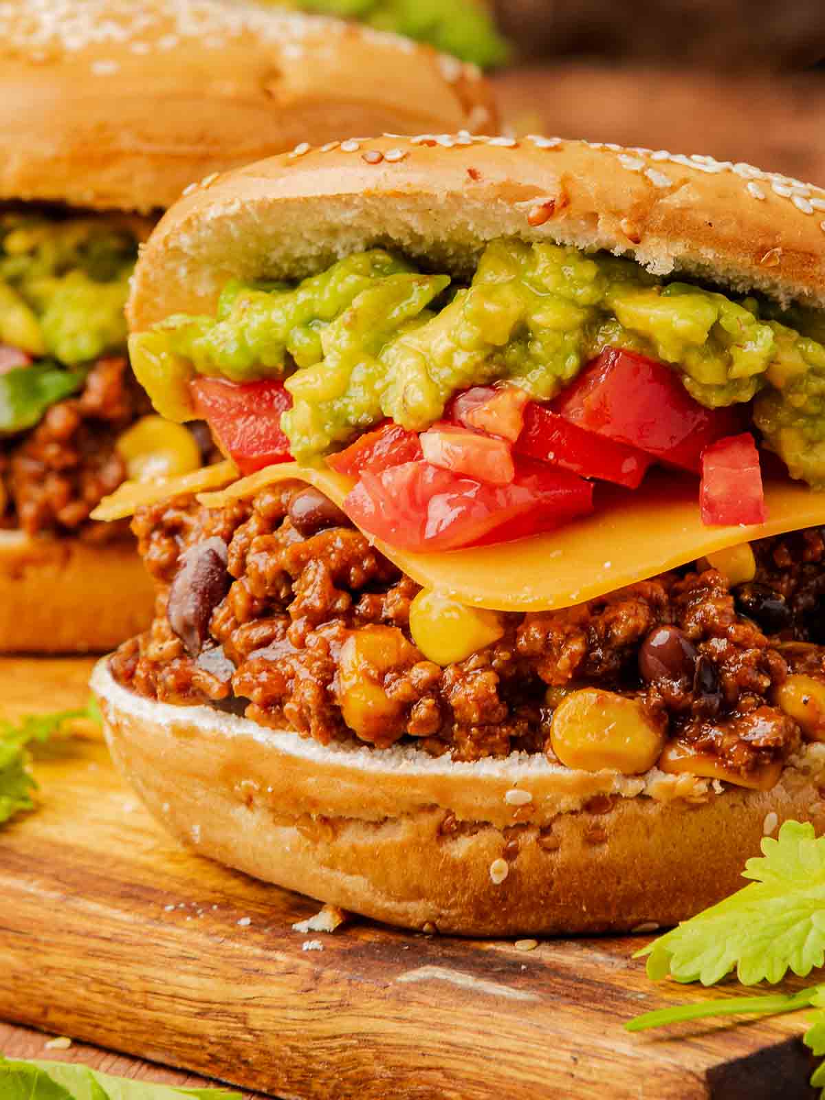 Close-up of the taco meat filling loaded with corn and beans under layers of guacamole and fresh tomatoes.