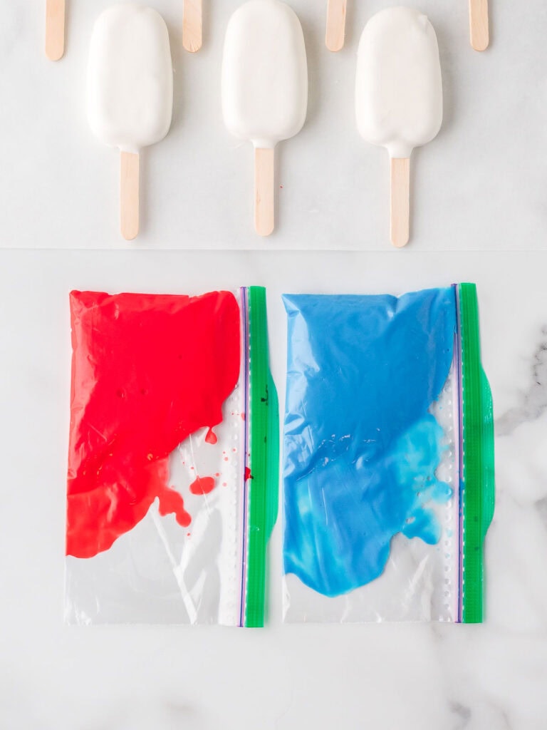 Red and blue icing transferred to ziplock bags for easy piping onto the cakesicles.