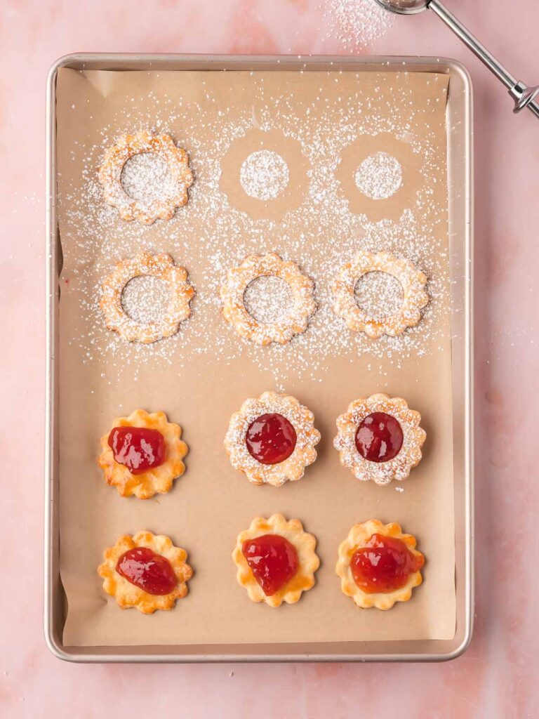 Top and bottom cookies lined up on a tray, with some stacked to show the filling inside.