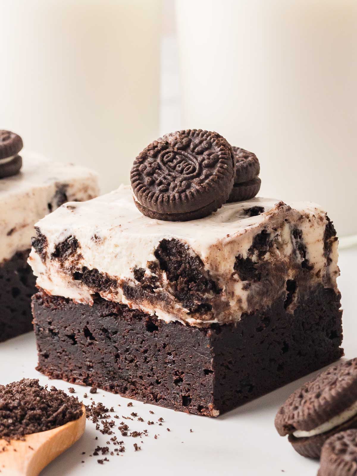 Close-up of an Oreo cheesecake brownie with a thick fudgy base, creamy cookies and cream topping, and a mini Oreo on top.