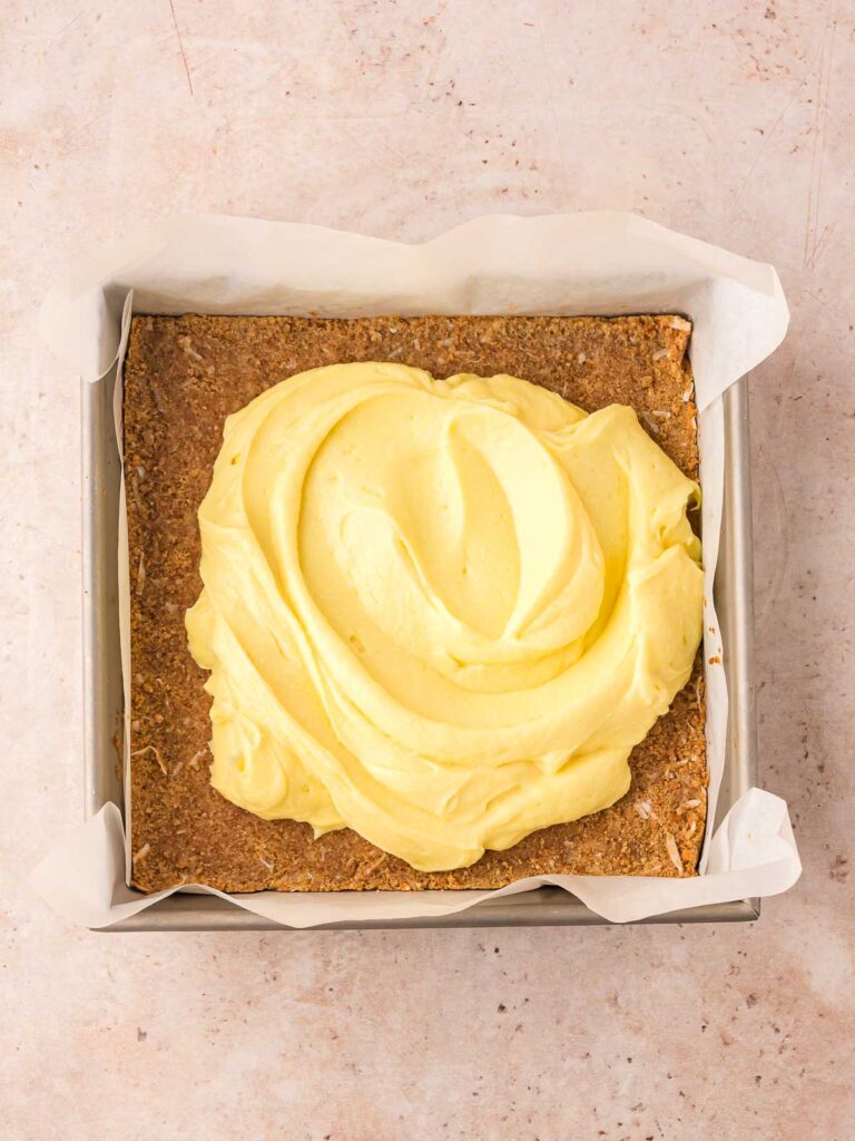 Thick vanilla coconut pudding spread over chilled graham cracker crust in square pan.
